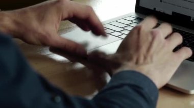 Kafenin ahşap masasında otururken dizüstü bilgisayarda çalışan bir adamın elleri. Kafede dizüstü bilgisayar ve telefonlarla örgütlenmeyi tartışarak..
