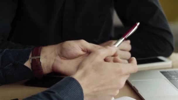 Hands of two cheerful business mans discussing something while sitting at the cafe with a laptop and phones. Two young successful colleagues in discussing organization moments by table in cafe. — ストック動画