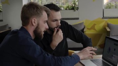 İki neşeli iş adamı bir şey tartışıyor ve kafede dizüstü bilgisayar ve telefonlarla otururken gülümsüyor. İki başarılı genç meslektaşımız, kafeteryadaki organizasyon anlarını teker teker tartışıyor..