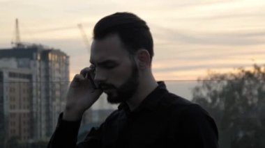 Genç işadamı dışarıda bir arkadaşıyla, iş ortağıyla ya da meslektaşıyla konuşarak akıllı telefon kullanıyor..