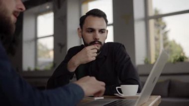 İki neşeli iş adamı bir şey tartışıyor ve kafede dizüstü bilgisayar ve telefonlarla otururken gülümsüyor. İki başarılı genç meslektaşımız, kafeteryadaki organizasyon anlarını teker teker tartışıyor..