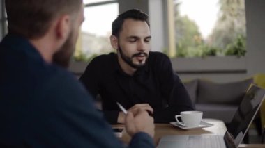 İki neşeli iş adamı bir şey tartışıyor ve kafede dizüstü bilgisayar ve telefonlarla otururken gülümsüyor. İki başarılı genç meslektaşımız, kafeteryadaki organizasyon anlarını teker teker tartışıyor..