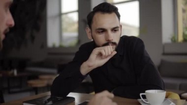 İki neşeli iş adamı bir şey tartışıyor ve kafede dizüstü bilgisayar ve telefonlarla otururken gülümsüyor. İki başarılı genç meslektaşımız, kafeteryadaki organizasyon anlarını teker teker tartışıyor..