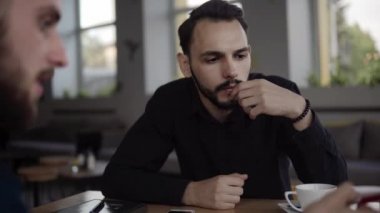 İki neşeli iş adamı bir şey tartışıyor ve kafede dizüstü bilgisayar ve telefonlarla otururken gülümsüyor. İki başarılı genç meslektaşımız, kafeteryadaki organizasyon anlarını teker teker tartışıyor..