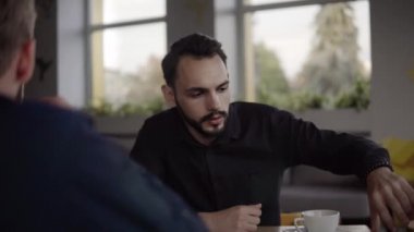 İki neşeli iş adamı bir şey tartışıyor ve kafede dizüstü bilgisayar ve telefonlarla otururken gülümsüyor. İki başarılı genç meslektaşımız, kafeteryadaki organizasyon anlarını teker teker tartışıyor..