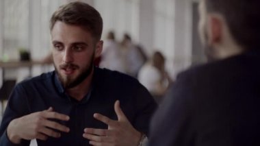 İki neşeli iş adamı bir şey tartışıyor ve kafede dizüstü bilgisayar ve telefonlarla otururken gülümsüyor. İki başarılı genç meslektaşımız, kafeteryadaki organizasyon anlarını teker teker tartışıyor..