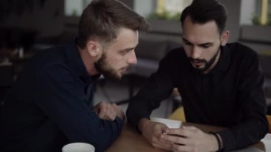 İki neşeli iş adamı bir şey tartışıyor ve kafede dizüstü bilgisayar ve telefonlarla otururken gülümsüyor. İki başarılı genç meslektaşımız, kafeteryadaki organizasyon anlarını teker teker tartışıyor..