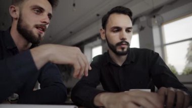 İki neşeli iş adamı bir şey tartışıyor ve kafede dizüstü bilgisayar ve telefonlarla otururken gülümsüyor. İki başarılı genç meslektaşımız, kafeteryadaki organizasyon anlarını teker teker tartışıyor..