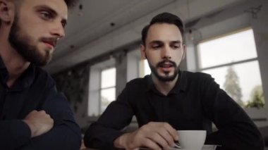 İki neşeli iş adamı bir şey tartışıyor ve kafede dizüstü bilgisayar ve telefonlarla otururken gülümsüyor. İki başarılı genç meslektaşımız, kafeteryadaki organizasyon anlarını teker teker tartışıyor..