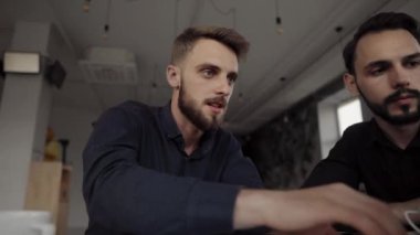 İki neşeli iş adamı bir şey tartışıyor ve kafede dizüstü bilgisayar ve telefonlarla otururken gülümsüyor. İki başarılı genç meslektaşımız, kafeteryadaki organizasyon anlarını teker teker tartışıyor..