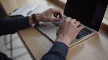 Kafenin ahşap masasında otururken dizüstü bilgisayarda çalışan bir adamın elleri. Kafede dizüstü bilgisayar ve telefonlarla örgütlenmeyi tartışarak..