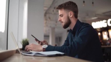Genç yakışıklı işadamı konferans odasında defterinin önünde oturuyor ve iş ortağıyla ya da üniversitelerle konuşmak için akıllı telefon kullanmaya başlıyor..
