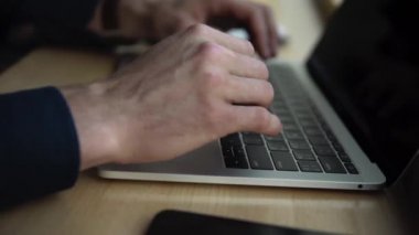 Kafenin ahşap masasında otururken dizüstü bilgisayarda çalışan bir adamın elleri. Kafede dizüstü bilgisayar ve telefonlarla örgütlenmeyi tartışarak..