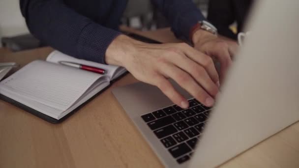 Hands of businessman with a top view of man working on laptop while sitting at the wooden desk at cafe. Discussing organization moments by table in cafe with a laptop and phones. — Stock Video