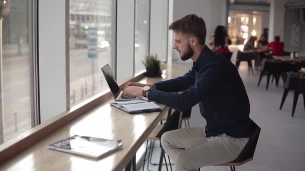 Jonge knappe zakenman zit voor zijn notebook in coferoom. — Stockvideo