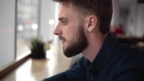 Joven hombre de negocios guapo sentado frente a su cuaderno en coferoom . — Vídeos de Stock