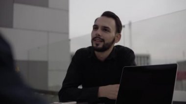 İki iş adamı akşam vakti dışarıda dizüstü bilgisayar ve telefonlarla oturup bir şeyler tartışıyor ve gülümsüyor. Organizasyon anlarını tartışan iki başarılı genç meslektaşım.