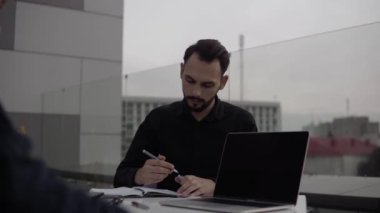 İki iş adamı akşam vakti dışarıda dizüstü bilgisayar ve telefonlarla oturup bir şeyler tartışıyor ve gülümsüyor. Organizasyon anlarını tartışan iki başarılı genç meslektaşım.