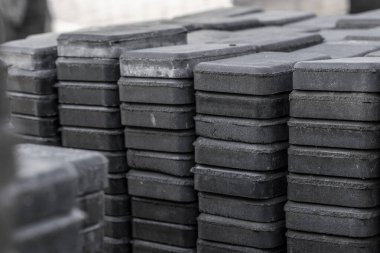 İnşaat alanında kaldırım taşı yığını. Yığınlar halinde istiflenmiş kaldırım taşları için tuğlalar, arka plan dokusu yapısı. Asfalt yolu için gri tuğlalar.