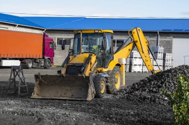 Sarı dört çekerli kepçe doldurucu bahçede duruyor. İnşaat alanında Workind için hazır..