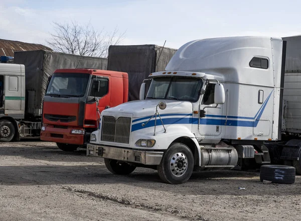 Moderne vrachtwagens van verschillende kleuren en modellen zijn betrokken bij het vervoer van verschillende soorten commerciële goederen zijn in een rij op truckstop in afwachting van de voortzetting van werkvluchten. — Stockfoto