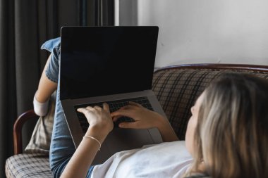 Kanepede dizüstü bilgisayarı olan bir kadın. İnternette çalış ve çalış, serbest çalış. Serbest çalışan bir kadın, defteriyle çalışan bir kız telefonla koltukta yatıyor, akıllı telefon ve kitap okuyor..