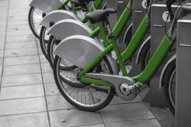 Sokak taşımacılığı yeşil hibrit bisikletler ve şehirde dolaşmak için elektronik ödeme formu kiralık ağ otoparkında sıra bekleyip bisikletçilerin bisiklet yolculuğu yapmasını bekliyor..