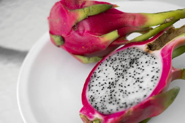 Frutto del drago. Vibrante Dragon Fruit su sfondo bianco. Fetta di frutta drago bianco o pitaya su piatto bianco sul tavolo, primo piano. Frutti tropicali ed esotici. Concetto di cibo sano e vitaminico . — Foto Stock