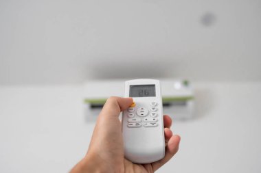 Uzaktan kumanda kullanan adam eli. Beyaz bir duvara monte edilmiş klimanın el tutma rc ve ayar sıcaklığı. Indooor konfor sıcaklığı. Sağlık kavramları ve enerji tasarrufu.