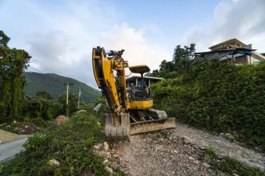 Günbatımında gökyüzü olan modern kazı alanı. Geniş çaplı bir kazı aracı yeşil çimlerle kaplı bir tepede duruyordu. Kırsal kesimde yeni bir bina inşa etmek için makineler.