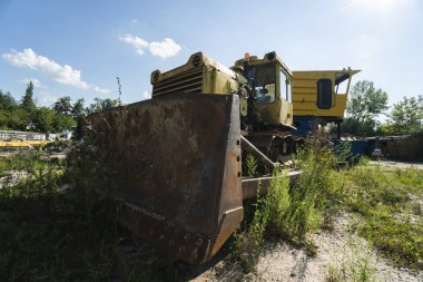 Güneşli bir günde tarlada eski sarı paslı traktör.