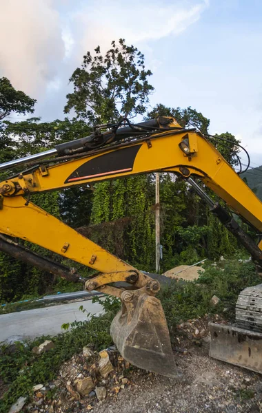 De moderne graafmachine op de bouwplaats met zonsondergang hemel. Grote gespoorde graafmachine op een heuvel met een groen gras. Machines voor de bouw van een nieuw gebouw op het platteland. — Stockfoto