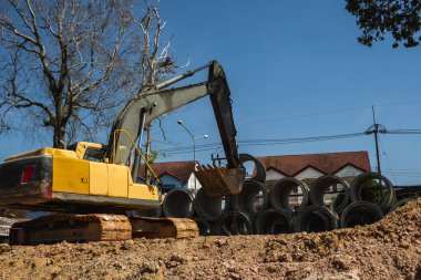 Büyük boruları bir araca aktarmak için kazıcı kullanmak.