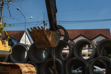 Büyük boruları bir araca aktarmak için kazıcı kullanmak.