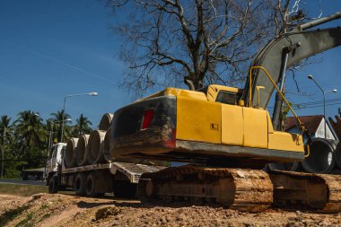 Büyük boruları bir araca aktarmak için kazıcı kullanmak.
