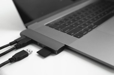 USB Tip-C adaptörlü USB kablosu ve SD kartı olan bir laptop. Laptop için C tipi konektörün altındaki USB adaptörü. Çok farklı portları olan bir bilgisayar için çok portlu istasyon. İnbot Dönüştürücü.