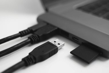 USB Tip-C adaptörlü USB kablosu ve SD kartı olan bir laptop. Laptop için C tipi konektörün altındaki USB adaptörü. Çok farklı portları olan bir bilgisayar için çok portlu istasyon. İnbot Dönüştürücü.