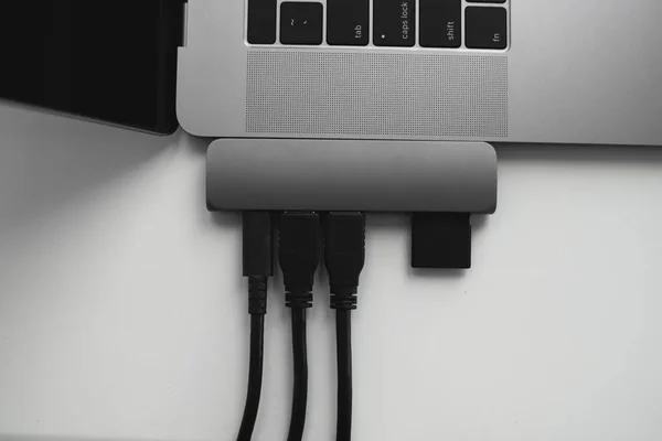 Portátil con adaptador USB Tipo-C con cables USB enchufados y tarjeta SD. El adaptador USB debajo del conector Tipo-C para portátil. Estación multipuerto para portátil con múltiples puertos diferentes. Convertidor Hub. —  Fotos de Stock