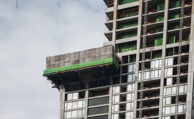 Mavi gökyüzüne karşı vinçleri olan yüksek katlı bir bina inşa etme şantiyesi.