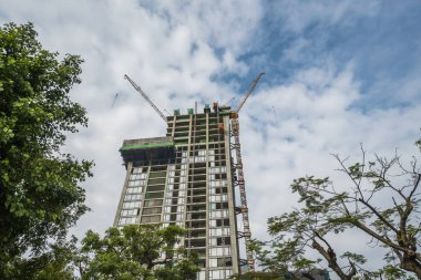 Mavi gökyüzüne karşı vinçleri olan yüksek katlı bir bina inşa etme şantiyesi.