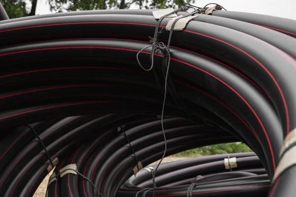 Tubos de borracha ou plástico preto com linhas vermelhas como material de construção e equipamentos no canteiro de obras. Usando como um tubo de água . — Fotografia de Stock