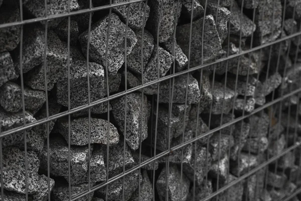 Un mur de pierre qui utilise le métal et la pierre en harmonie. Écologie conviviale en utilisant des ressources naturelles pour la construction. Murs en pierre pour bloquer la pierre qui s'effondre. Mur en pierre recouvert d'un filet . — Photo