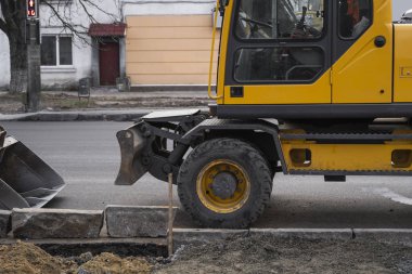 Sarı kazıcı caddedeki bir yolun şantiyesinde duruyor. Ağır endüstri. Bir yol inşaatı.