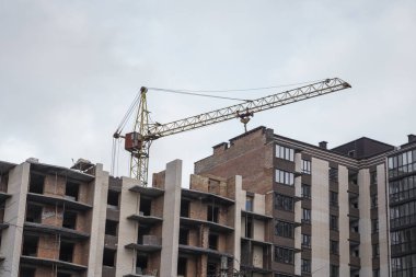 Mavi gökyüzüne karşı vinç ve inşaat alanı. İnşaatın bitmemiş binasının metal inşaatı. Crane kulesi çok katlı depo inşaatı için kullanılıyor.
