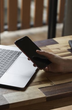 Kadın eli bilgisayarlı akıllı telefon kullanır. İnternette çalış ve çalış, serbest çalış. Serbest çalışan ya da serbest çalışan bir kadın, dizüstü bilgisayarıyla çalışan bir kız ahşap masada oturan bir telefon ve okuyucu..