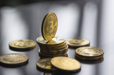 Masanın yansıyan bir yüzeyinde altın bitcoin paraları yığını. Sanal kripto para birimi kavramı. Sanal para madenciliği. Bitcoin ticareti.