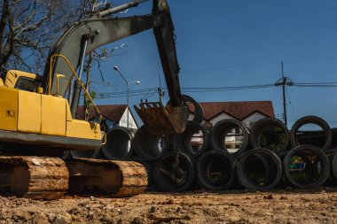 Büyük boruları bir araca aktarmak için kazıcı kullanmak.