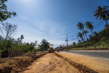 Tayland, Phuket - 12 Aralık 2018: Yeni yol inşaatında çalışan yol silindirleri. Otoyolda çalışan ağır iş makineleri. İnşaat malzemeleri. Yolun sıkıştırması.