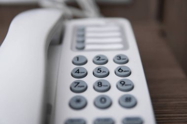 Otelde kahverengi bir masada gri coplar ile beyaz vintage telefon.