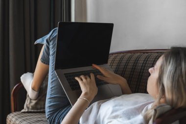 Kanepede dizüstü bilgisayarı olan bir kadın. İnternette çalış ve çalış, serbest çalış. Serbest çalışan bir kadın, defteriyle çalışan bir kız telefonla koltukta yatıyor, akıllı telefon ve kitap okuyor..